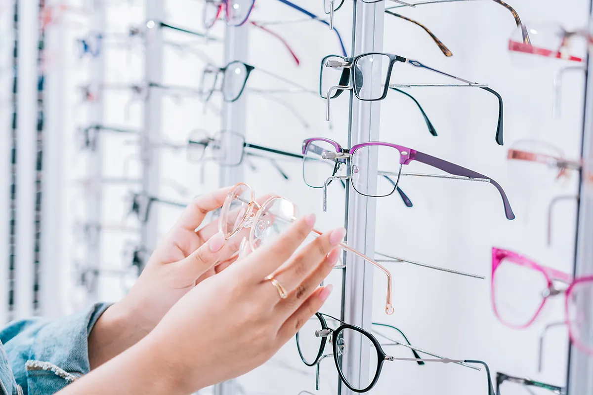 a close-up of a pair of hands picking up glasses in an optical